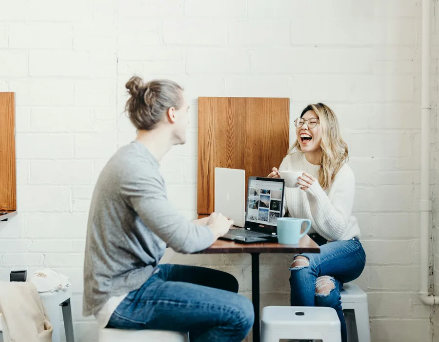 Two people chatting over coffee and a laptop